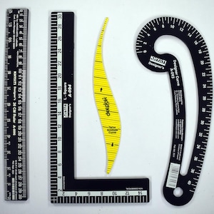 May include: A set of black and yellow drafting tools, including a 30 cm ruler, a right angle square, a curved ruler, and a tailor's armhole curve. The tools are marked with measurements in centimetres and inches.