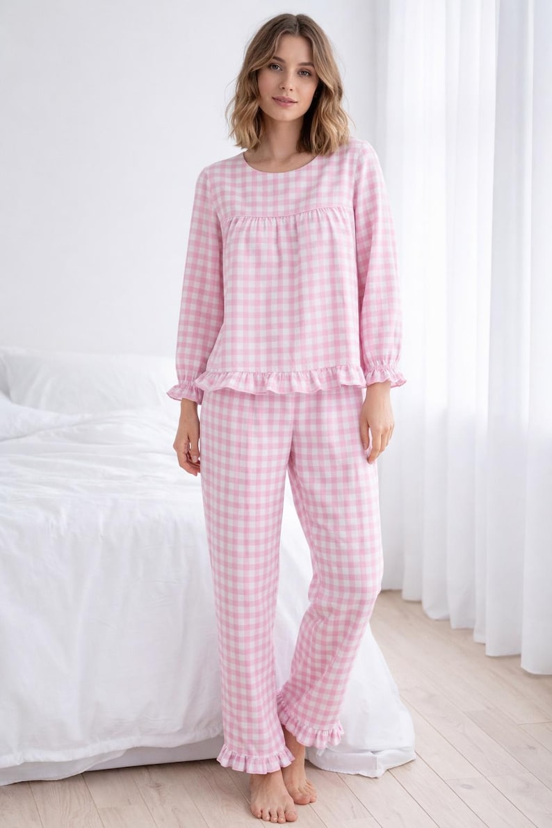 May include: Pink and white gingham pajama set. The long-sleeved top has a round neckline and ruffle trim at the cuffs and hem. The matching pants also have ruffle trim at the ankles. The pajamas are made of a soft, comfortable fabric.