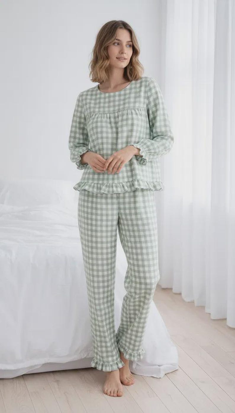 May include: A light green and white checkered pajama set. The long-sleeved top has a round neckline and ruffle trim at the cuffs and hem. The matching pants also have ruffle trim at the ankles. The pajamas are made of a soft, lightweight fabric.