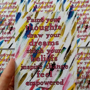 May include: A greeting card featuring the text "Paint your thoughts, draw your dreams, stitch your beliefs, inspire change, feel empowered" in pink. The background has colourful brushstrokes in yellow, blue, pink, and black.