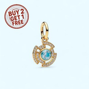 Może przedstawiać: Złoty wisiorek z centralnym, jasnoniebieskim kamieniem szlachetnym, otoczony okrągłym wzorem z przezroczystymi, błyszczącymi akcentami. Wisiorek ma małą pętlę na łańcuszek. Obraz zawiera również okrągłą grafikę z tekstem "BUY 2 GET 1 FREE".