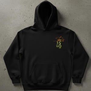 May include: Black hooded sweatshirt with a kangaroo pocket and a drawstring hood. The sweatshirt features a small, colorful graphic on the upper left chest. The graphic is a stylized design in shades of green and orange, with the text "Stay 4" above it.