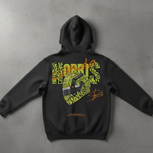 May include: Black hooded sweatshirt with a graphic design on the back. The design features the name "NORRIS" in a neon green and orange color scheme, along with a stylized racing helmet and signature. The text "BEAT YOUR TEAM MATE" is also visible.