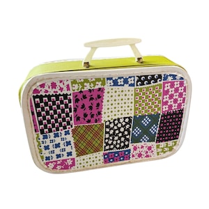 Puede incluir: Una maleta rectangular con un patrón de patchwork de varios diseños florales, de cuadros y de lunares en tonos rosa, verde, negro y blanco. La maleta tiene un asa de plástico blanco y un panel superior de color verde lima con borde blanco.