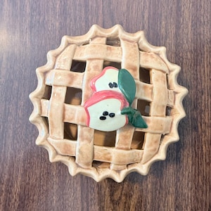 Puede incluir: Una taza de cerámica blanca con un diseño floral colorido. La taza tiene un asa y un acabado brillante. Las flores son en tonos de rosa, morado y amarillo, con hojas verdes. La taza es para bebidas calientes.