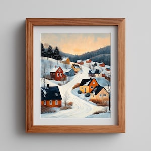 May include: A framed print of a winter village scene. The artwork depicts colorful houses nestled in a snowy landscape, with a winding road leading through the village. The sky transitions from orange to blue, suggesting a sunrise or sunset.