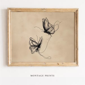 May include: A framed print featuring two abstract butterfly illustrations in black line art on a beige background. The print is in a gold-colored frame. The text "MONTAGU PRINTS" is at the bottom.