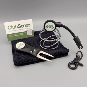 May include: A golf accessory set including a black and silver ball retriever, a divot repair tool, a microfiber towel, and an instruction card. The set features a black clip and a metal ball holder. The text "ClubScoop" is visible on the items.