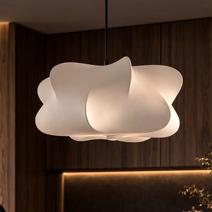 May include: A modern white pendant light fixture with a unique, cloud-like design hangs above a kitchen island. The light is suspended from a black cord, and the kitchen features dark wood cabinetry and a black countertop.
