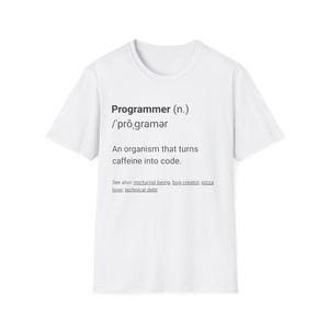 May include: White t-shirt featuring the definition of "Programmer" in black text. The definition includes the pronunciation and the phrase "An organism that turns caffeine into code."
