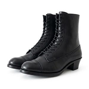 May include: A pair of black leather lace-up boots featuring a rounded toe with decorative brogue detailing, a mid-calf height shaft, and a stacked block heel. The boots have matching black laces threaded through metal eyelets and a stitched sole.