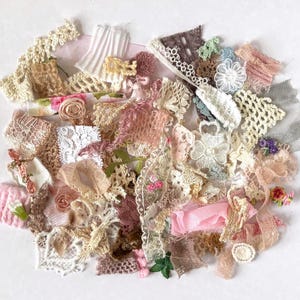May include: A collection of assorted lace and fabric trim scraps in various textures and patterns. The assortment includes pieces in shades of white, cream, beige, pink, brown, and green, featuring floral motifs, crochet work, and pleated ribbons.