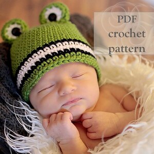 May include: A green crocheted frog hat with black and white stripes. The hat has large black eyes and a small green nose. The hat is on a baby's head. PDF crochet pattern.