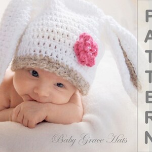 May include: A white crochet bunny hat with long ears and a pink flower accent. The hat has a tan brim and is worn by a baby. The text "Baby Grace Hats" is visible. The word "PATTERN" is also visible.