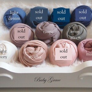 May include: A selection of rolled fabric in various colors, including light denim, taupe, army green, light ivory, cinnamon mocha, and mauve. Some items are marked "sold out". The items are arranged in a white decorative tray with the text "Baby Grace".