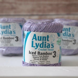 May include: Three spools of lavender colored Aunt Lydia's Iced Bamboo Crochet Thread. The label reads "Iced Bamboo 3" and "Viscose from Bamboo".