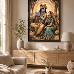 May include: A framed wall art print depicting the Hindu deities Krishna and Radha. Krishna has blue skin, wears gold jewelry, and plays a wooden flute. Radha sits beside him in a teal and gold sari. The scene features lotus flowers and a golden halo.