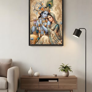 K&ouml;nnte beinhalten: Gerahmtes Kunstwerk, das ein Paar in traditioneller indischer Kleidung zeigt. Die Figuren sind in sanften Blau- und Goldt&ouml;nen gehalten, mit aufwendigen Details. Das Kunstwerk h&auml;ngt an einer wei&szlig;en Wand &uuml;ber einem Holzschrank.