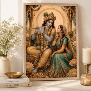 May include: A framed wall art print depicting Krishna playing a golden flute while seated beside Radha. The figures are adorned in intricate gold and teal garments, jewelry, and floral garlands, set against a backdrop of ornate pillars and lotus flowers.