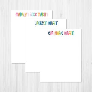 May include: Three white rectangular stationery sheets featuring personalized names printed in a colorful, rounded sans-serif font at the top. The names displayed are Madalyn Rose Martin, Jackson Martin, and Eva Marie Martin in various bright hues.