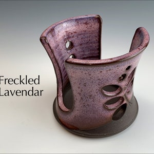 May include: A ceramic dish soap dispenser with a lavender glaze and a cutout butterfly design. The dispenser is labeled "Freckled Lavendar".