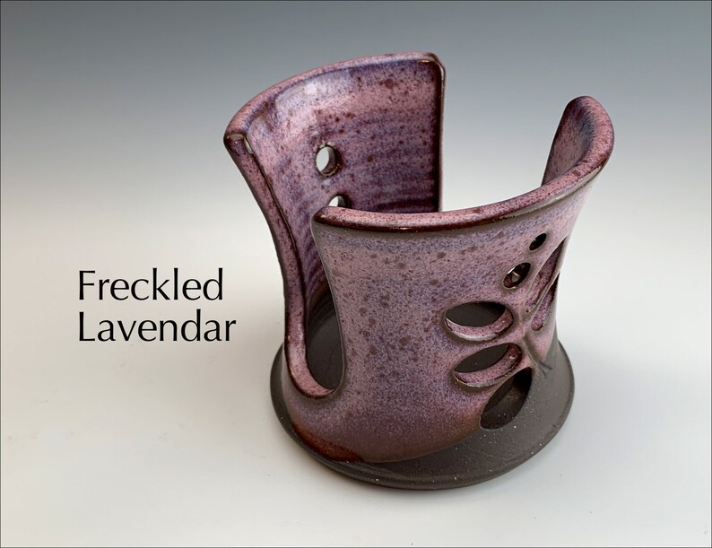 May include: A ceramic dish soap dispenser with a lavender glaze and a cutout butterfly design. The dispenser is labeled "Freckled Lavendar".