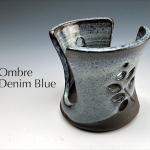 May include: A ceramic soap dish with a leaf design in a blue and brown ombre glaze. The dish is designed to hold a bar of soap and has drainage holes.