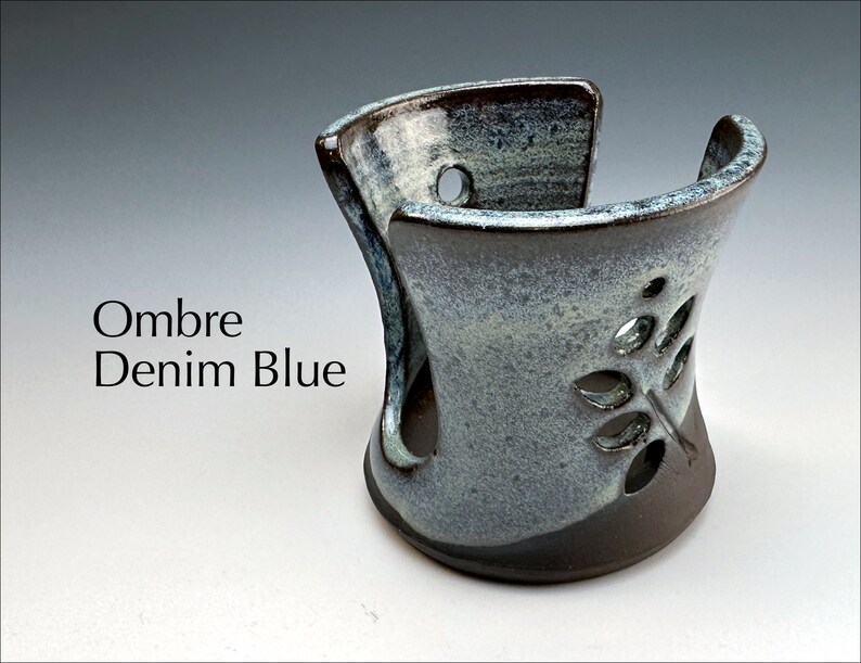 May include: A ceramic soap dish with a leaf design in a blue and brown ombre glaze. The dish is designed to hold a bar of soap and has drainage holes.