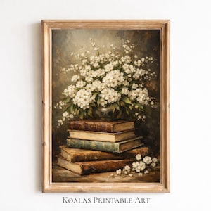 Puede incluir: Una impresión enmarcada de estilo vintage que presenta una naturaleza muerta de un ramo de flores blancas en un jarrón sobre una pila de libros antiguos. Los libros tienen cubiertas marrones y verdes. El texto "KOALAS PRINTABLE ART" está en la parte inferior.
