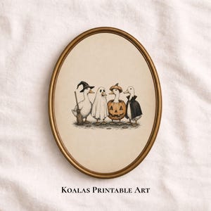 May include: An oval-framed wall art print featuring an illustration of four ducks in Halloween costumes: one as a witch with a broom, one as a ghost, one inside a jack-o'-lantern, and one wearing a black cape. The text Koalas Printable Art is below.