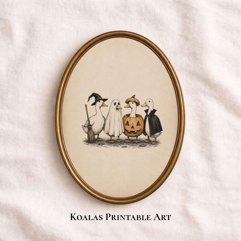 May include: An oval-framed wall art print featuring an illustration of four ducks in Halloween costumes: one as a witch with a broom, one as a ghost, one inside a jack-o'-lantern, and one wearing a black cape. The text Koalas Printable Art is below.