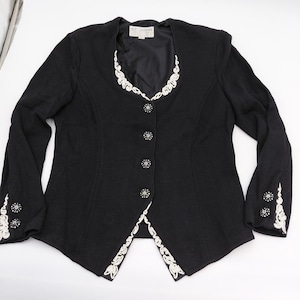 May include: A black blazer with white embroidered trim and decorative buttons. The blazer features a V-neck design and long sleeves. The brand name "ST JOHN" is visible on the label.