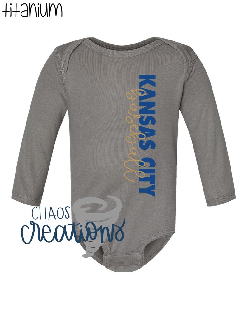 May include: Grey long-sleeved baby onesie with the text "KANSAS CITY basketball" in blue and gold lettering.
