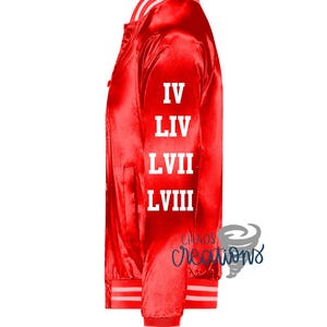Puede incluir: Chaqueta bomber de sat&eacute;n rojo con rayas blancas en el cuello y los pu&ntilde;os. La chaqueta tiene texto blanco en la manga izquierda que dice "IV LIV LVII LVIII".