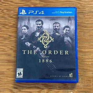 以下が含まれることがあります： PlayStation 4用ゲームソフト「The Order: 1886」の青いケース。パッケージには、暗い時代の衣装を着た4人のキャラクターが街並みを背景に描かれています。タイトルは白文字で印刷されており、左下にはESRB Mレーティングのロゴがあります。