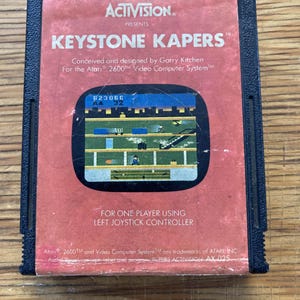 Peut inclure: Une cartouche de jeu vidéo Keystone Kapers vintage pour l'Atari 2600. L'étiquette rouge présente le titre du jeu, une capture d'écran et le logo Activision. La cartouche est noire et montre des signes d'usure.