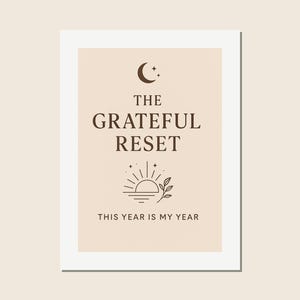 May include: A framed print with a light beige background and white border. The text "THE GRATEFUL RESET" is in dark brown, with a crescent moon and stars above, and a sun and leaf design below. The phrase "THIS YEAR IS MY YEAR" is at the bottom.