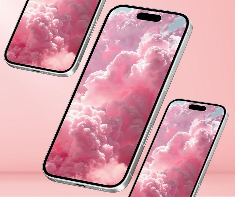 May include: Three silver smartphones with screens displaying a pink cloudscape. The phones are angled, showcasing the screen's wallpaper against a soft pink background. The screens have a black notch at the top.
