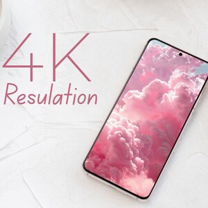 May include: A smartphone with a pink cloud wallpaper, angled on a white surface. The phone's screen displays a vibrant image of fluffy pink clouds. The text "4K Resolution" is written in pink above the phone.
