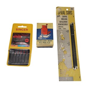 May include: A collection of vintage sewing notions, including a yellow Singer needle package, a small box for an automatic needle threader, and a package of spiral stays. The Singer package displays the text "6 Premium Regular Point Red Band Needles".