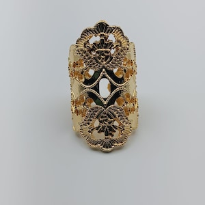May include: A gold-colored ring with an ornate, openwork design. The ring features repeating floral and scroll patterns, creating a detailed and elegant appearance. The ring is a statement piece, suitable for special occasions.