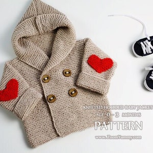 Op de afbeelding: Een beige gebreide babyjas met een capuchon en rode hart-applicaties. De jas heeft een dubbele knoopsluiting met houten knopen. De tekst "KNITTED HOODED BABY JACKET AGE 0-3 MONTHS PATTERN www.ZoomYummy.com" is onderaan de afbeelding gedrukt.