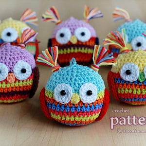 Op de afbeelding: Zes kleurrijke gehaakte uil-versieringen met regenboogstrepen en zwarte ogen. De uilen hebben kleine gehaakte antennes. De tekst "crochet pattern by ZoomYummy.com" staat onderaan de afbeelding.