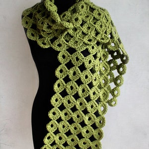 Può includere: Una sciarpa di uncinetto verde con un motivo a rombi. La sciarpa è drappeggiata su un manichino nero. Il testo "crochet pattern" e "ZoomYummy.com" è visibile nell'immagine.