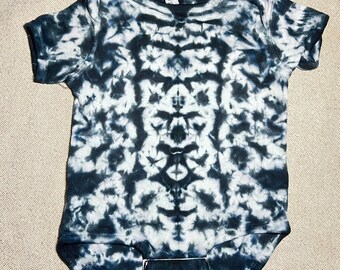 Puede incluir: Un body de bebé de color negro y blanco con un patrón de tie-dye simétrico.