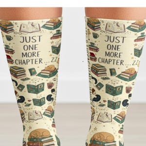 May include: Cream-colored socks with a repeating pattern of books, coffee cups, and sleeping cats. The text "JUST ONE MORE CHAPTER... ZZ" is printed on the socks. The socks are designed for comfort and style.