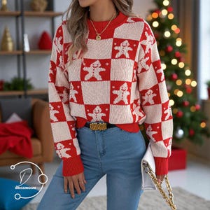 Może przedstawiać: Czerwony i kremowy sweter z wzorem szachownicy z motywami ludzików z piernika. Sweter ma okrągły dekolt i prążkowane mankiety. Modelka ma na sobie niebieskie dżinsy i złoty pasek. Biała torebka ze złotym łańcuszkiem jest w ręce modelki.