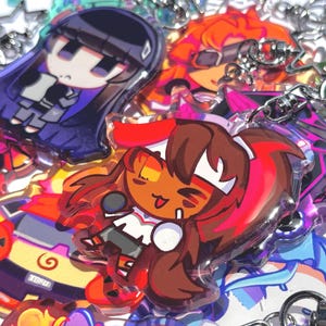 Może przedstawiać: Kolekcja przezroczystych akrylowych breloków z kolorowymi ilustracjami postaci w stylu anime. Zawieszki przedstawiają różne postacie o odmiennych kolorach włosów, strojach i wyrazach twarzy, każda przymocowana do srebrnego metalowego karabińczyka.