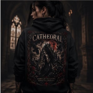 Puede incluir: Una sudadera negra con capucha que presenta un gran gráfico en la espalda. El diseño incluye la palabra CATHEDRAL en fuente gótica, una figura central, rosas rojas, una calavera y aves oscuras. El texto bajo la figura dice LORD OF DREAMS BORN TO DIE.