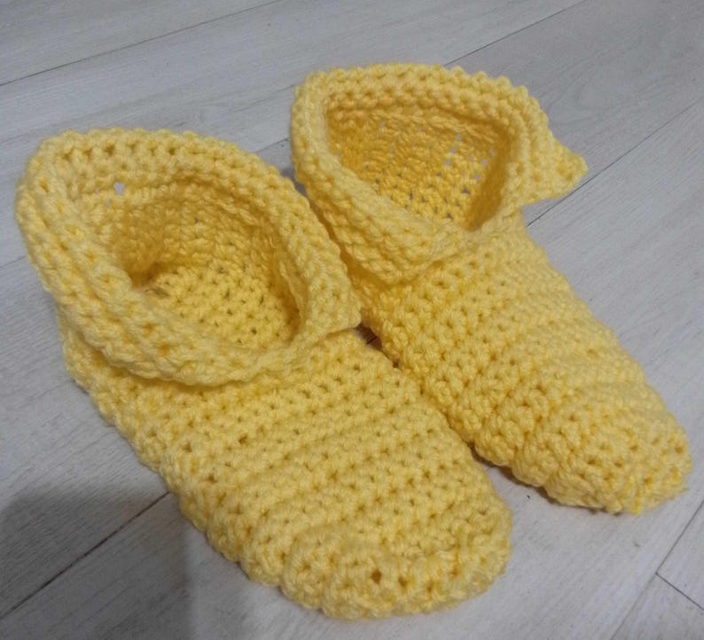 Pu&ograve; includere: Un paio di pantofole all'uncinetto gialle fatte a mano. Le pantofole hanno uno stile stivaletto con un risvolto. La maglia all'uncinetto crea una superficie strutturata. Le pantofole sono progettate per l'uso in casa.